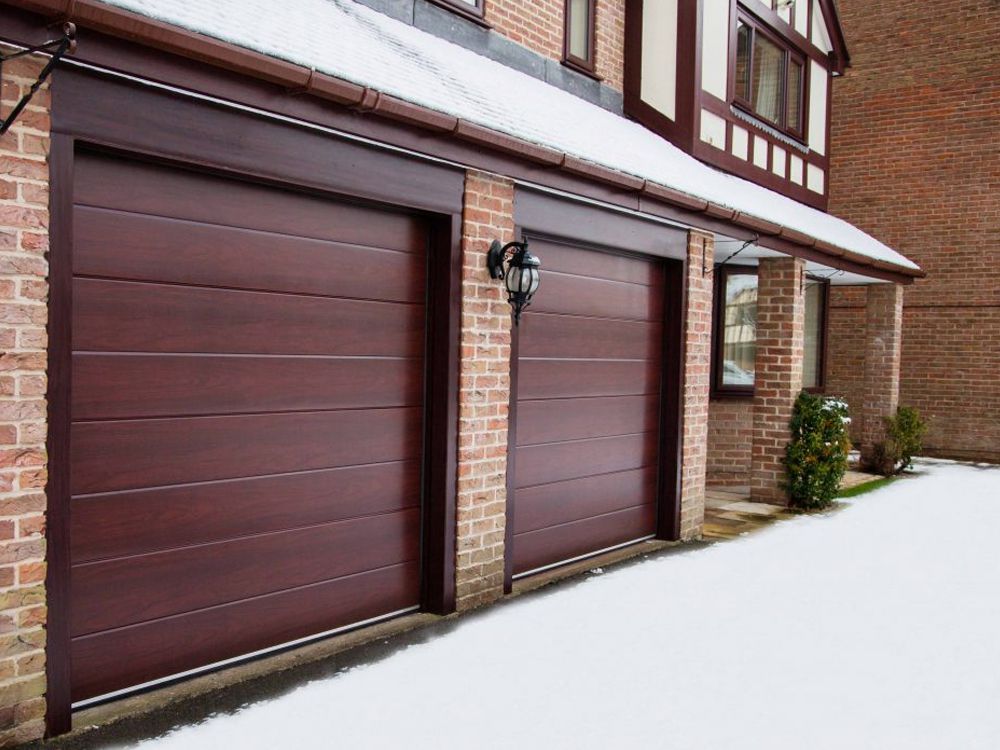 Uși de garaj secționale maro montate pe casă cu cărămidă — proiect TERMOCLASS